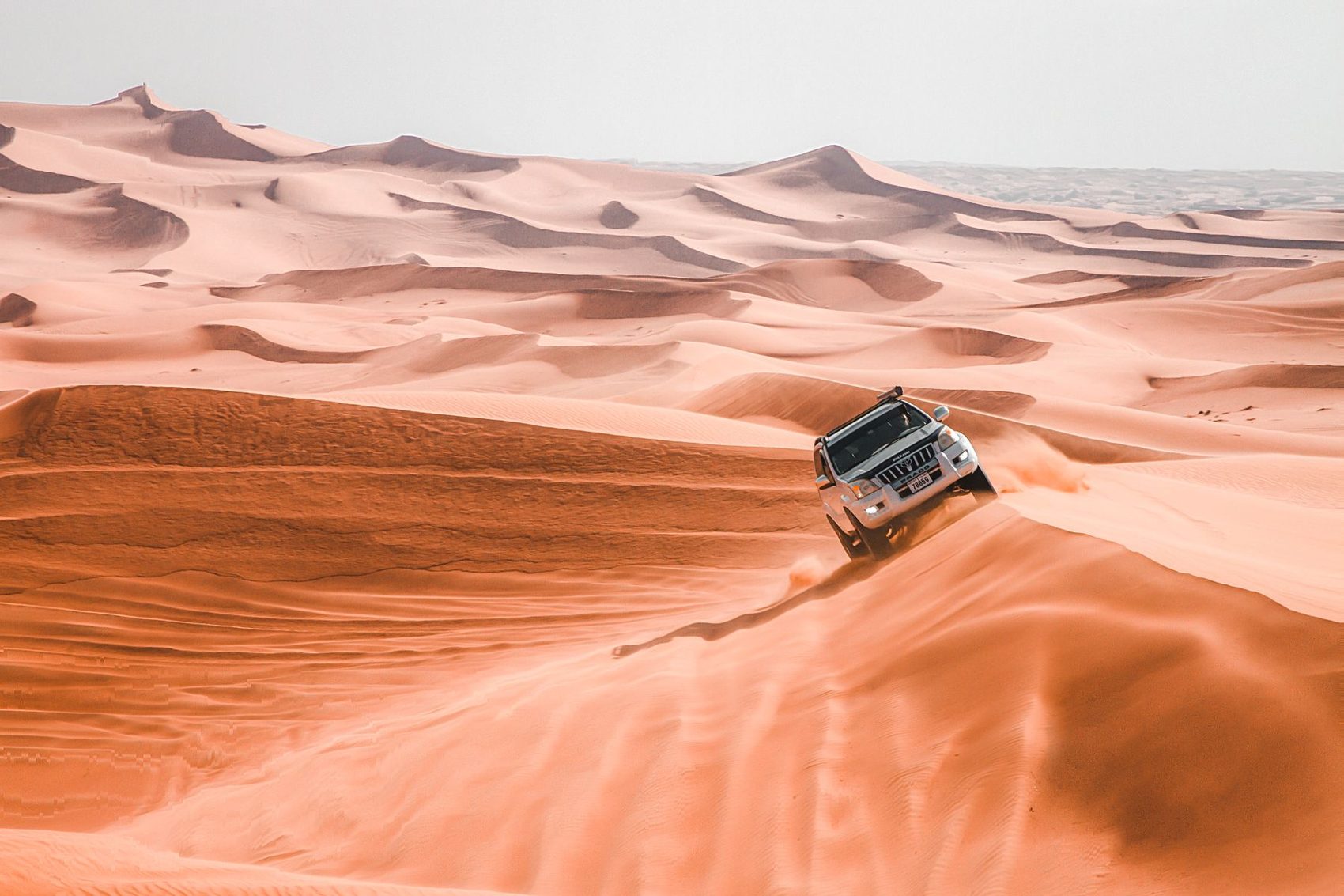 4x4 vehicle driving across the desert dunes for an optional excursion from Grand Dune Luxury Camp near Merzouga
