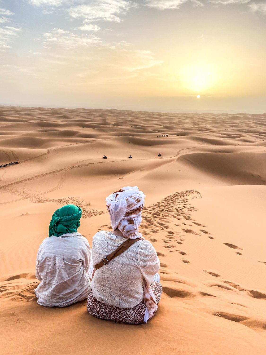 Two travellers watching the sunset over the Moroccan desert sands of Merzouga