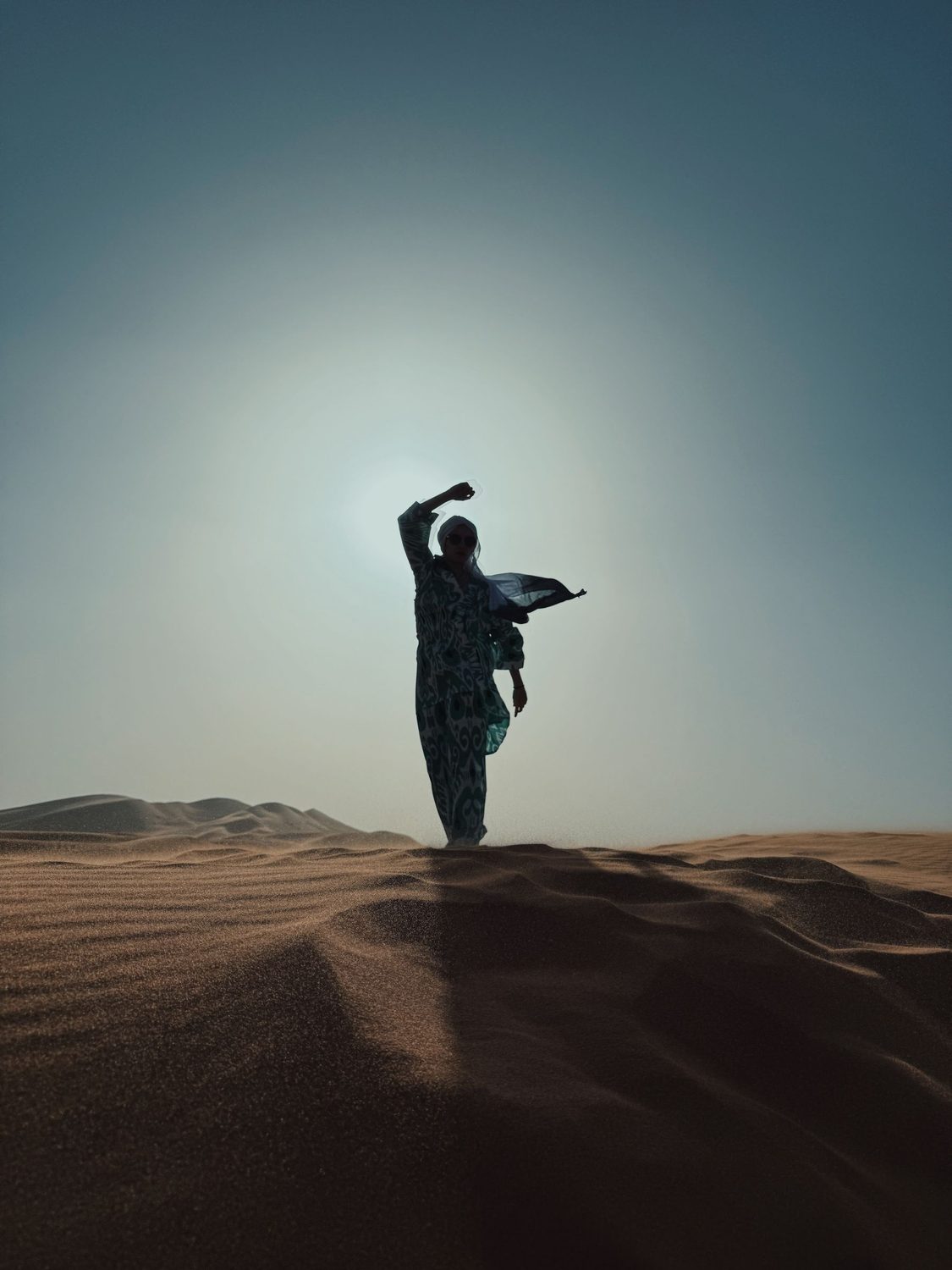 Silhouette of a person standing on a desert dune as the sun sets over the Sahara